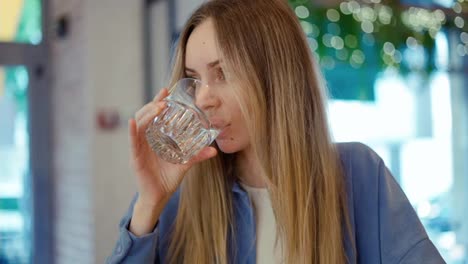 Mujer-Joven-Bebiendo-Agua-En-Una-Cafetería