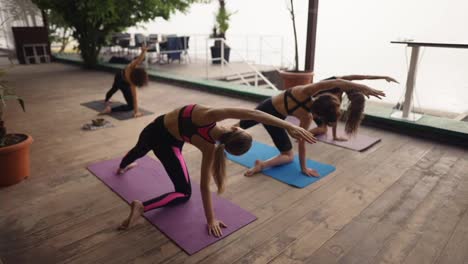 People-on-yoga-class-together-outdoors,-diverse-girls-on-terrace-doing-stretching