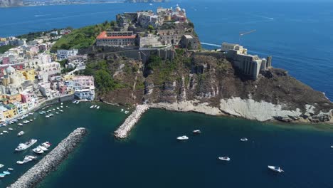 Medieval-Church-of-Procida-Islands-at-Marina-Corricella-port,-Waterfront-colourful-housing-surrounded-by-seawater,-Italy,-Aerial-Shot