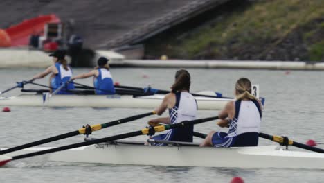 Tracking-shot-of-a-double-scull-of-women-leaning-on-oars-during-a-rowing-race