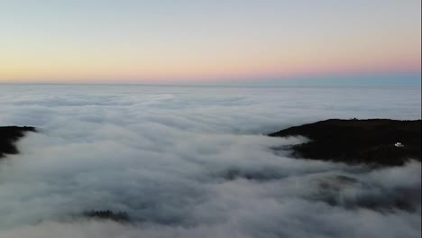 Luftaufnahmen-über-Dem-Dichten-Nebel-Oder-Den-Wolken,-Von-Denen-Nur-Die-Berggipfel-Des-Blauen-Himmels-Hell-Erleuchtet-Zu-Sehen-Sind