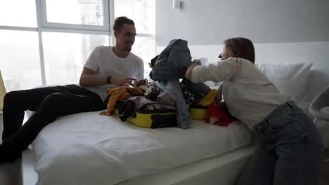 Young-family-making-fun-while-packing-for-holiday.-Caucasian-man,-woman-and-child-in-bedroom.-Little-kid-is-sitting-in-the-small