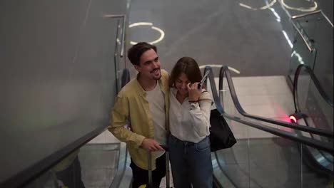 Loving-couple-on-the-escalator-at-the-airport.-A-guy-and-his-girlfriend-are-traveling-together.-Going-up-with-passports-and