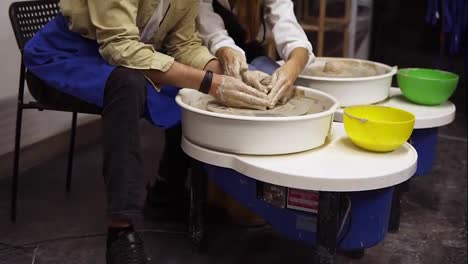 Cheerful,-smilling-couple-having-fun-while-working-together-in-potter-workshop.-Sitting-by-potter's-wheel,-marking-each-other-noses-with-clay.-Slow-motion