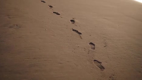 Tracking-Close-Up-footage-of-footprints-on-the-golden-wet-sand-at-beach