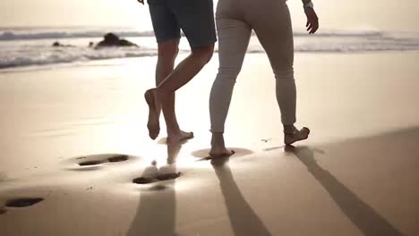 Honeymoon-married-young-couple-on-beach-walking-in-love-holding-hands-at-romantic-sunrise.-Woman-and-man-relaxing-on-travel-vacation-holidays,-wearing-casual