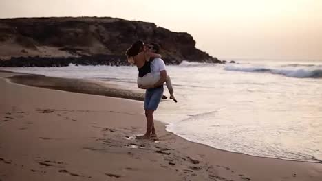 Couple-in-love.-Man-in-shirts-turning-around-his-lovely-woman-on-beach-and-sensually-kissing.-Full-length-view-of-happy-young-barefoot-man-and-woman-having-fun-together-on-sandy-beach