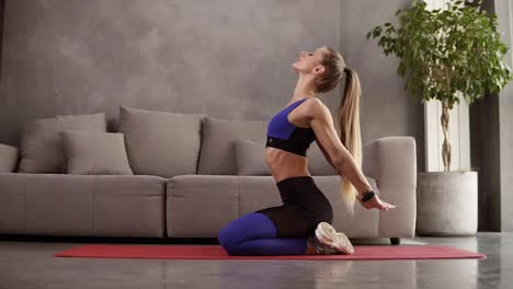 Junge-Frau-Trainiert-Zu-Hause-Yoga,-Sitzt-Auf-Einer-Matte-Vor-Dem-Sofa-Und-Dehnt-Ihre-Rückenmuskulatur,-Indem-Sie-Sich-Beugt,-Während-Sie-Auf-Dem-Boden-Sitzt.-Gesunder-Und-Sportlicher-Lebensstil