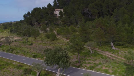 Motorbike-is-driving-on-road-surround-by-nature-on-mallorca-island,-aerial