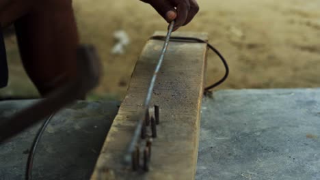 carpenter-hammering-piece-of-steel-metal-iron-in-rural-remote-indian-village-close-up-artisan-hands