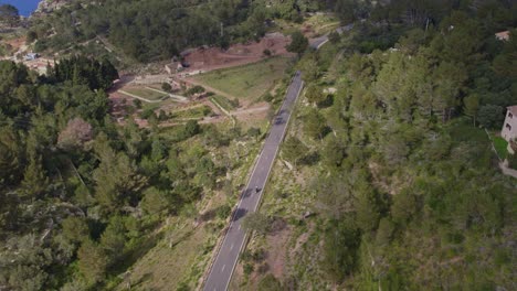 Following-shot-of-motorbike-driving-on-mountain-road-on-Mallorca-island,-aerial