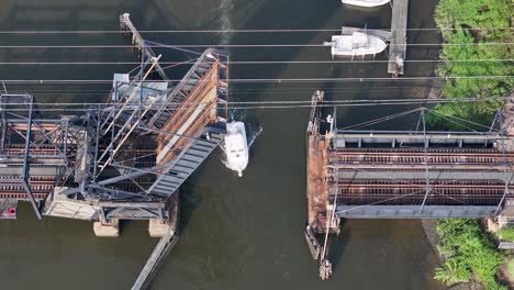 Boat-passing-beneath-open-railroad-drawbridge-on-Cheesequake-Creek-in-Morgan,-NJ