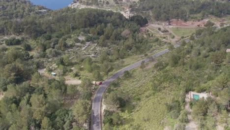 Wide-shot-of-road-between-green-vegetation-on-mallorca-island,-aerial