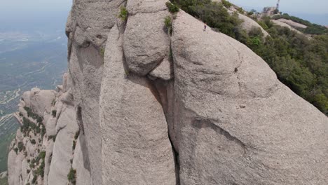 Luftaufnahme-Eines-Mannes,-Der-Auf-Dem-Felsen-Der-Einzigartigen-Berge-Rund-Um-Das-Kloster-Montserrat-Steht,-Luftaufnahmen-In-Spanien,-Europa