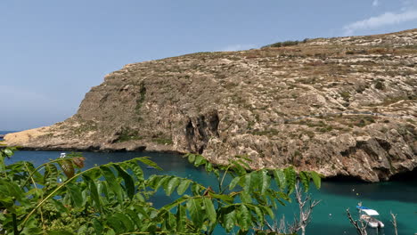 Majestic-drone-view-of-Xlendi-Bay,-a-picturesque-beach-in-Gozo,-Malta,-surrounded-by-high-cliffs,-magnificent-views-and-crystal-blue-water