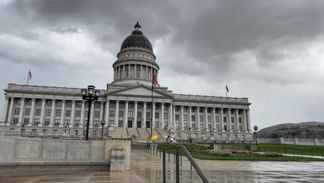 Outside-looking-at-front-of-Utah-State-capital-building-on-an-overcast-gloomy-day-seeing-a-few-protesters-standing-around-as-camera-starts-panning-and-moving-off-to-the-right