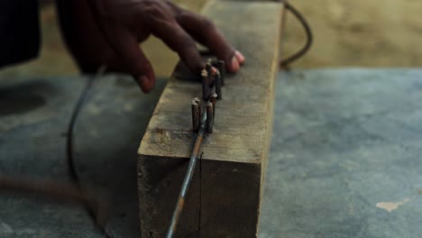 manual-bending-iron-steel-in-construction-site-African-black-male-carpenter-hands-close-up