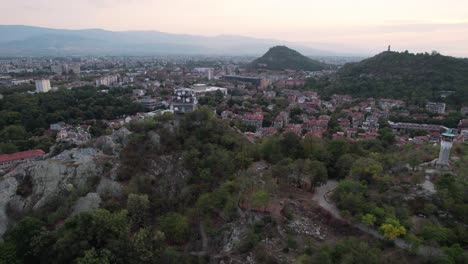 Aerial-cityscape-view-of-Plovdiv-city-in-Bulgaria,-flying-by-old-clock-tower
