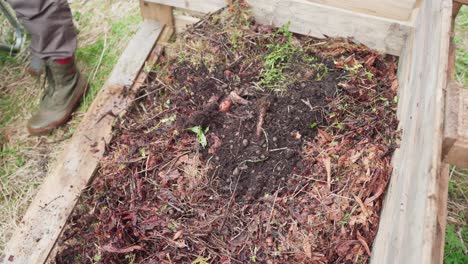 Gardener-Filling-Raised-Garden-Bed-With-Compost-Pile