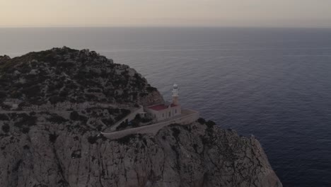 Orbit-of-lighthouse-at-Dragonera-Island-Mallorca-during-sunset,-aerial