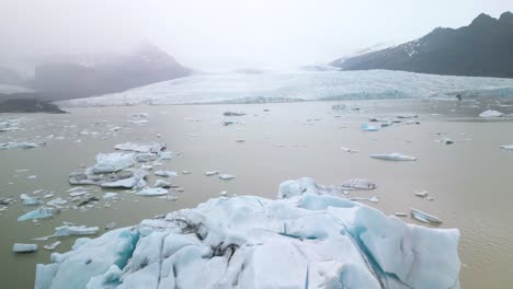 Filmische-Drohnenaufnahme-Eines-Großen-Eisbergs-Mit-Gletscher-Im-Hintergrund