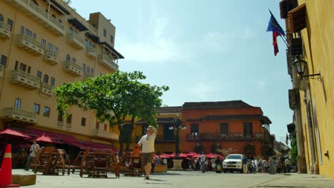 Man-walks-past-apartments,-cafe,-buildings-in-Cartagena
