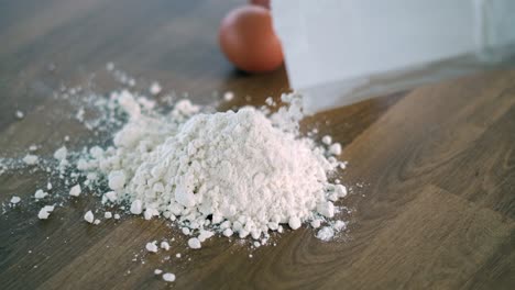 Person-sprinkling-flour-on-table-next-to-eggs-to-prepare-a-dough