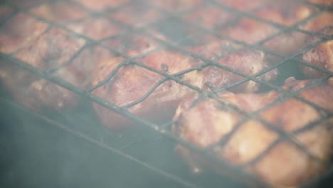 Close-up-shot-of-juicy-and-marinated-chicken-leg-meat-on-bbq-grid,-smoke-in-slow-motion