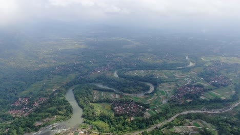 Winding-river-and-towns-in-Indonesia-landscape,-aerial-drone-view