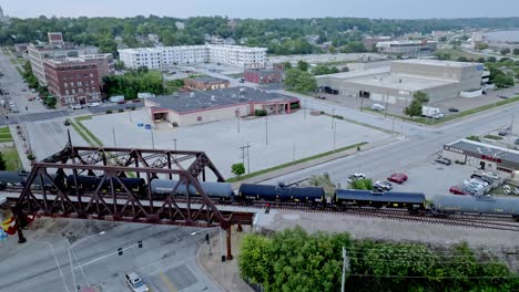 Train-moving-over-Mississippi-River-railroad-bridge-in-Davenport,-Iowa-with-drone-video-stable