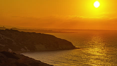 Zeitraffer-Eines-Goldenen-Sonnenuntergangs-über-Der-Küste-Eines-Meeres-Und-Der-Klippe