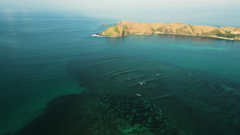 Aerial-over-the-coastline-of-surfers-catching-a-big-wave-together-near-Kuta-in-the-south-of-Lombok-Island,-Indonesia