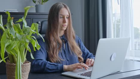 Cute-young-caucasian-woman-concentrating-on-working-with-laptop-at-office-desk