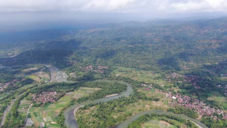 Winding-river,-township-and-endless-landscape-of-Indonesia,-aerial-drone-view