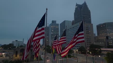 American-flags-waving-in-front-of-Detroit,-Michigan-skyline