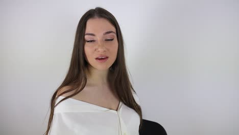 Slow-motion-clip-of-an-attractive-female-model-singing-in-a-white-room-while-sitting-on-a-chair