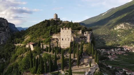Revealing-drone-shot-of-a-castle-on-a-mountain-near-Lake-Garda,-Italy