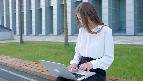 Upset-young-junior-woman-working-frustrated-and-grimacing-on-laptop-in-office-outdoors