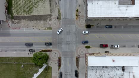 Intersection-in-downtown-Marshalltown,-Iowa-with-traffic-moving-and-drone-video-overhead-moving-down