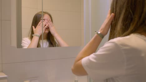 Nervöses-Teenagermädchen,-Das-Im-Badezimmerspiegel-Schaut-Und-Lacht