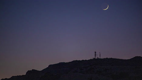 Timelapse-of-the-crescent-moon-in-motion-at-night-over-a-mountain