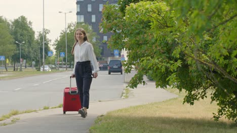 Young-businesswoman-walking-along-road-with-a-suitcase
