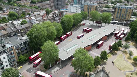 Bus-terminal-Walthamstow-central-East-London-drone,-aerial-buses-moving-in-and-out-of-station