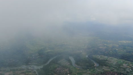 Dense-clouds-above-small-town-of-Indonesia,-high-altitude-drone-view