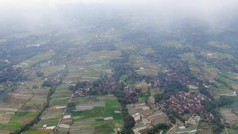 Misty-clouds-and-small-villages-in-Indonesia,-aerial-drone-view