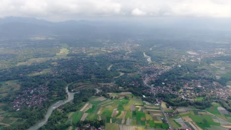 River-winding-through-small-villages-of-Indonesia,-aerial-drone-view