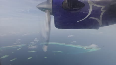 Window-view-of-spinning-airplane-engine-with-tropical-island-below