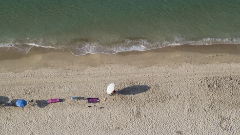Man-walks-across-empty-Mediterranean-beach-seen-from-above-4K