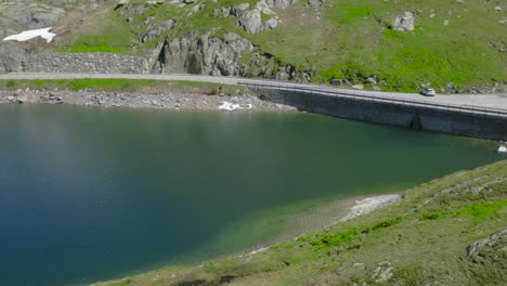 Carretera-De-Montaña-En-Los-Alpes-Suizos,-Pasando-Por-Un-Lago-Azul-Profundo