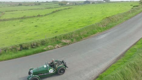 Beautiful-classic-cars-descending-a-Hill-to-Kilmurrin-Cove-Copper-Coast-Waterford-Ireland-early-summer
